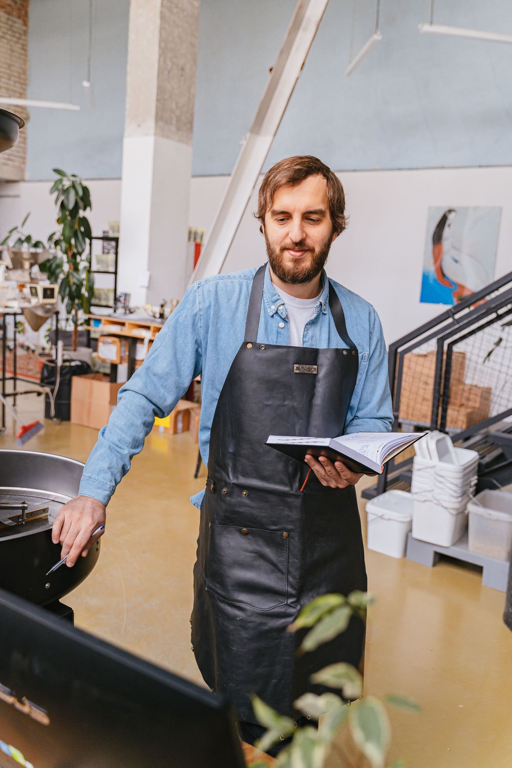 A cafe owner in an apron reviewing notes behind the counter